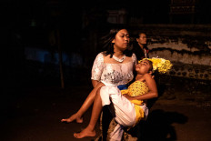 A Balinese woman carries a dancer, who is in a state of trance, during the performance. JP/Agung Parameswara