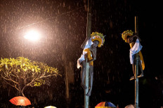 The dancers fearlessly climb up bamboo poles in the rain. JP/Agung Parameswara