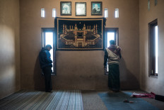  Two teenagers from the Azwawi family of Bakalan stand by the windows of their family room seeking a better signal so they can play games on their cell phones before heading into the fields for work. JP/Dottie Bond