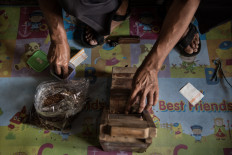 A man rolls a kretek cigarette on a small homemade machine in a warehouse in Parakan. JP/Dottie Bond