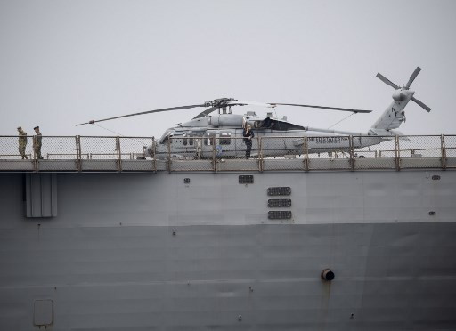 US Navy personnel walk past a Sikorsky MH-60 Seahawk helicopter on the deck of the USS Blue Ridge after the ship docked in Manila Bay on March 13, 2019. The US 7th Fleet flagship USS Blue Ridge arrived in Manila for the ship's port visit to conduct cooperative deployment with the Philippine Navy.