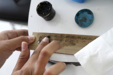 Candlenuts are used in the final process of writing on palm leaf. They add black color to the letter, while the oil makes the leaves more durable. JP/Arya Dipa
