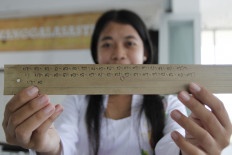 Udayana University student Siti Noviali shows Balinese script polished with candlenuts during a workshop at the Ajip Rosidi Library. JP/Arya Dipa