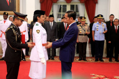 President Joko "Jokowi" Widodo puts a belt on Dewa Agung Ayu Alamanda Diastari at the inauguration of the national flag-hoisting team at the State Palace on Aug. 15. JP/Seto Wardhana