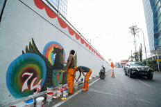 Jakarta’s Public Facility Maintenance Agency workers, often referred to as “orange troops”, draw the Bhinneka Tunggal Ika (Unity in Diversity) symbol on Slipi Jaya overpass in West Jakarta, on Aug. 17. JP/Donny Fernando