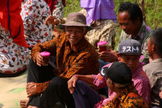 Villagers wait for a parade to pass by while sipping cups of tea. JP/Maksum Nur Fauzan