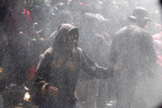 Students are sprayed with water from a police water cannon during a protest against the agrarian reform bill, the Criminal Code revision bill and other bills at the Malang Legislative Council building in East Java on Sept. 24. Antara/Ari Bowo Sucipto
