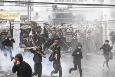 Protesters run after the police shoot tear gas to them in front of West Java Legislative Council in Bandung, West Java on Sept. 24. Earlier, about 2,500 protesters voiced their rejection on the bill on Criminal Code revision, Agrarian Reform bill, Correctional Facility bill and demand the government to cancel the Law on Corruption Eradication Commission. JP/Arya Dipa