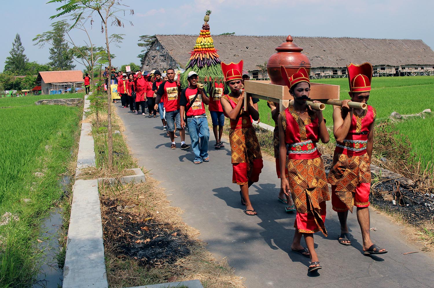 Residents carry clay water jugs, as well as offerings, through paddy fields and Pluneng village. JP/ Magnus Hendratmo