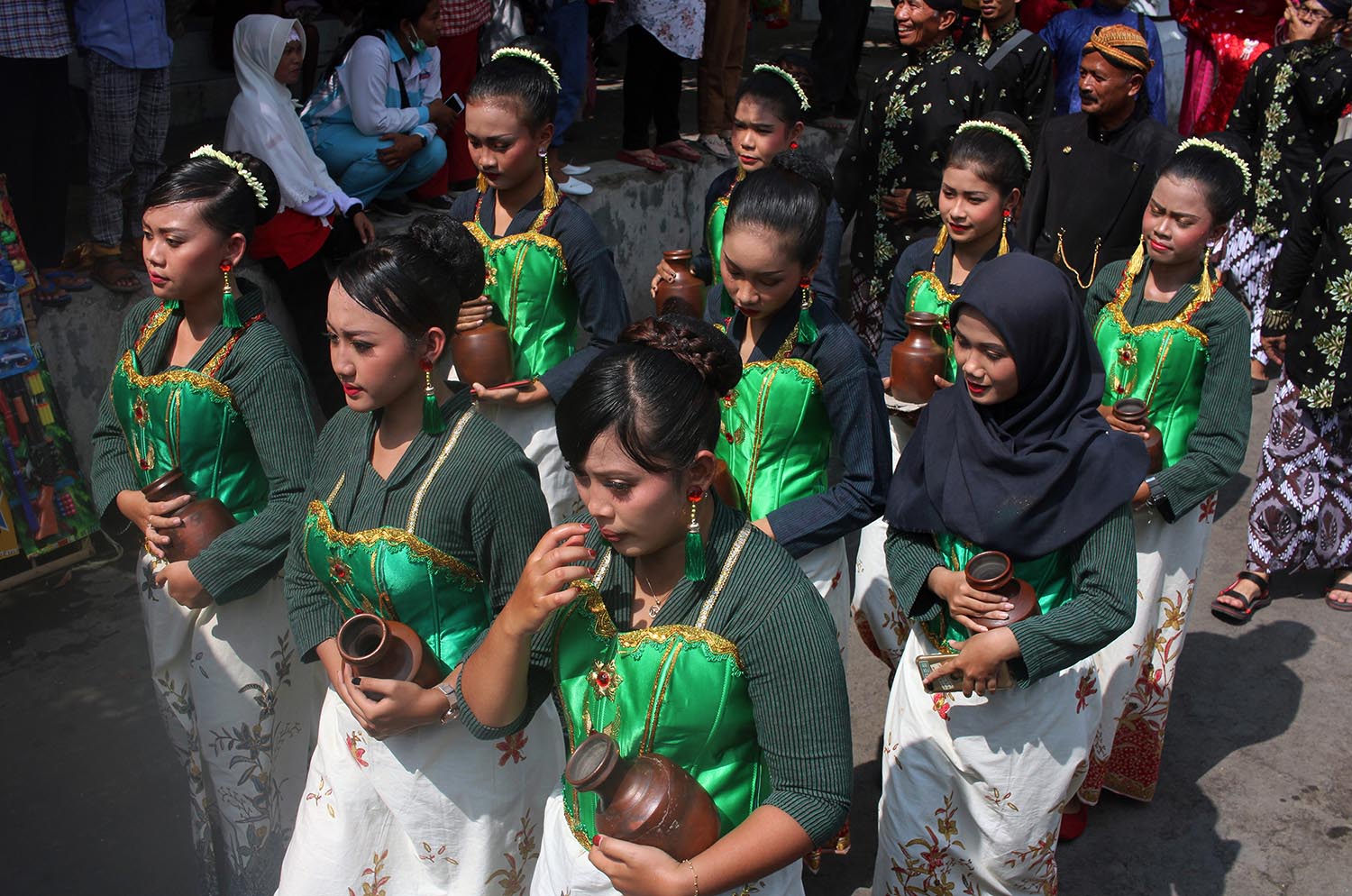 Teenage girls carry “klenting” (small clay water jugs). JP/ Magnus Hendratmo