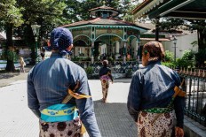 Pras, Rizki and Suyatiman walk to the exit after finishing their duties at the kraton. JP/ Anggertimur Lanang Tinarbuko