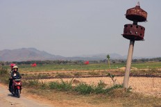 Dry reservoir: A motorcyclist and her passenger ride past a leaning, rusted post alongside the old road from Baturetno to Eromoko in Wonogiri, Central Java. The area becomes flooded up to the full height of the post when the Gajah Mungkur reservoir is full. JP/Magnus Hendratmo