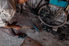 A barber sweeps away hairs on the barbershop floor. JP/Anggertimur Lanang Tinarbuko 