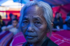 Pakuli Paulina, 63, sits beside the corpses of her parents and family members. JP/Yusuf Wahil