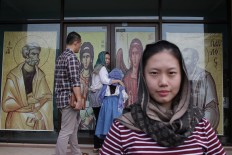 Converse with God: A woman poses in front of the Janasuci Petrus & Paulus Church in Tangerang  as others enter.  JP/ Taufan Wijaya