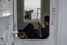 A passenger relaxes on the ferry while using his cell phone. JP/Rosa Panggabean