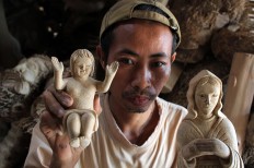The artist holds figures he created out of bamboo root. JP/Magnus Hendratmo