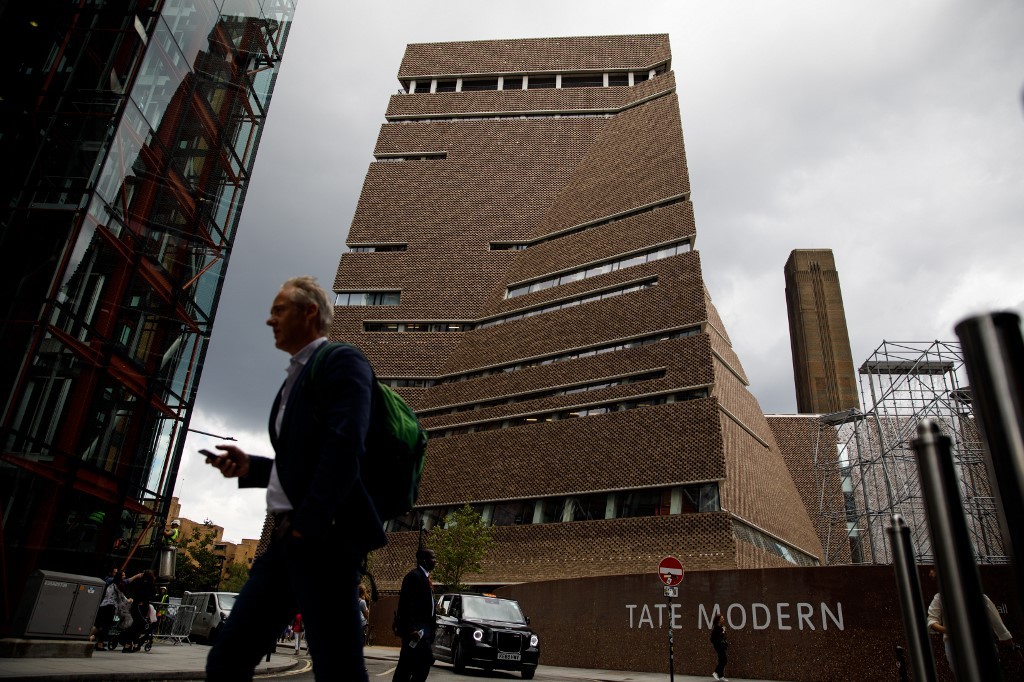 People walk past the Tate Modern gallery in central London on August 5, 2019. 