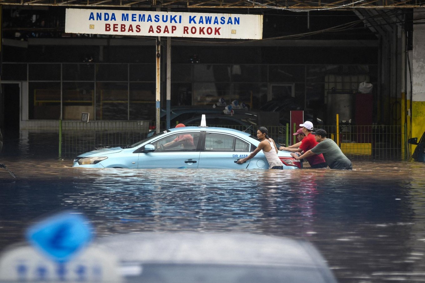 Residents move a car at the Blue Bird taxi pool in Kramat Jati, East Jakarta, on Jan. 1. Antara/Galih Pradipta