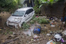 Residents stand near a damaged car after a flood in Cimareme, West Bandung, West Java, on Jan. 1. Antara/Novrian Arbi