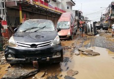 What remains: Residents walk by destroyed cars in Bekasi, West Java, on Thursday after massive flooding triggered by heavy rainfall hit the area. AFP/Bagus Saragih