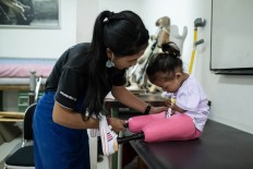 Putu helps Safitri put on her new pink prosthetic legs. JP/Agung Parameswara