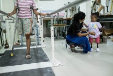 Putu chats with Safitri, while Ulil, 13, practices walking with the assistance of metal rails. Ulil lost her right leg as a toddler because of a malignant tumor. JP/Agung Parameswara