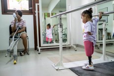 Safitri holds metal rails as she practices walking with her prosthetic legs. JP/Agung Parameswara