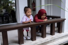 Safitri and her mother Sofiani look at a fish pond. “She is excited about going to school now that she’s the same height as everybody else,” Sofiani said of her daughter’s enthusiasm. JP/Agung Parameswara