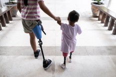Ulil and Safitri walk hand in hand as they practice with their prosthetic legs they have long waited for. JP/Agung Parameswara