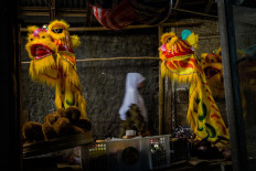 Finished products: A woman passes between two barongsai lion heads hung by Doel in front of his workshop. JP/Anggertimur Lanang Tinarbuko