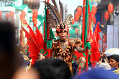 A tatung, in Dayak-inspired costume, has a thick metal stick stabbed through his cheek. JP/HS Putra