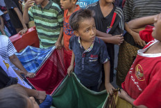 Open wide: Children use sarongs to collect sugar sachets. JP/Ramadhani