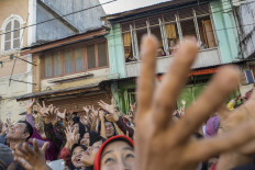 Hands up: Residents hold up their hands before trying to catch sachets of sugar in front of the Muhammadan Mosque in Padang, West Sumatra.  JP/Ramadhani