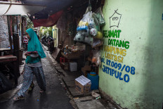 A woman walks past Gang Z on Feb. 4, 2020, where a painted sign welcomes people to the “kampung literasi” in Jatipulo subdistrict, West Jakarta. JP/Afriadi Hikmal