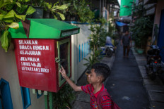 Ihsan, 11, looks for something to read in one of five book-sharing boxes that have been installed along the narrow alleys of the Jatipulo literacy kampung in West Jakarta. JP/Afriadi Hikmal