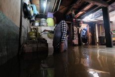 Life goes on: A local resident, Nurhayati, cooks in her flooded kitchen in Satria Raya Grogol, West Jakarta, on Tuesday. JP/Donny Fernando
