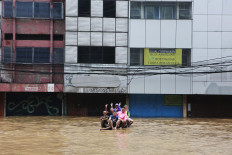 Chilling out: A number of people pose amid the floodwaters on Jl. Gunung Sahari, Central Jakarta, on Tuesday. JP/Seto Wardhana