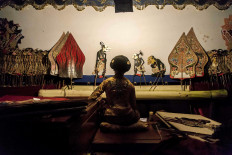 Dalang Dwi Puspita enjoys a quiet moment behind the screen of a wayang show before opening &ldquo;Punakawan&rdquo;. &ldquo;Punakawan&rdquo;, which follows a tragic event in the narrative, presents the four popular comic characters of Semar, Petruk, Bagong and Gareng, and is one of the most anticipated acts in a wayang show. JP/Irene Barlian