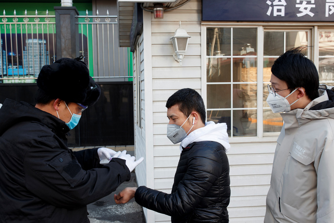 A security guard takes the temperature of people as they arrive for work at an office building in Beijing, as the country is hit by an outbreak of the novel coronavirus, China, March 3, 2020. 