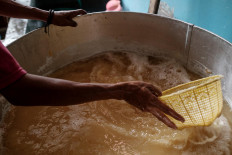 Hakim removes floating soybeans during the boiling process. These are of poor quality and will not be used to make tempeh. JP/ Anggara Mahendra
