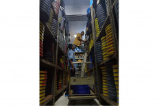 Watchful dedication: Firdaus (left) watches as Budi uses both hands to extract a reel case from an upper shelf of the film archive, which is located in the basement of Sinematek Indonesia. The two film preservation technicians are paid less than the minimum wage to maintain Indonesia's film heritage. JP/Xena Olivia