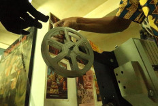 Manual loading: Archival staffer Firdaus prepares to mount a film reel in a projector. The film must then be threaded manually through the roller and film gate on the equipment. JP/Xena Olivia