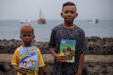 Two boys show the new books they received from an Armada Pustaka Mandar oral book review session at Waiwuring, East Flores. JP/ Yusuf Wahil