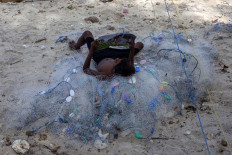 A boy lays atop a pile of fishing nets as he reads a book at Mali Beach on Alor Island, East Nusa Tenggara. JP/ Yusuf Wahil
