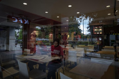 A restaurant employee finishes some paperwork among empty tables in Jl. Malioboro, Yogyakarta, on April 5. Some restaurants only serve take away, while many food stalls have decided to shut down. JP/ Arnold Simanjuntak
