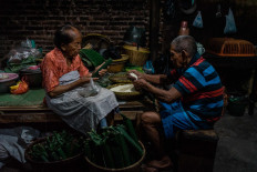 Satinem (left) and her husband Narto Utomo fill dozens of banana leaf tubes with glutinous rice. JP/Anggertimur Lanang Tinarbuko