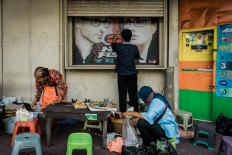 An optician staff members opens the shop’s window — a sign for Satinem to close her lupis stall. JP/Anggertimur Lanang Tinarbuko