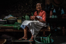 Satinem prepares to cook lupis, a traditional sweet snack. She forms a tube from a banana leaf, which will later be filled with glutinous rice. JP/Anggertimur Lanang Tinarbuko