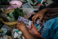 Satinem’s daughter, Mukinem, calculates the money they’ve earned after finishing selling lupis with her mother. JP/ Anggertimur Lanang Tinarbuko